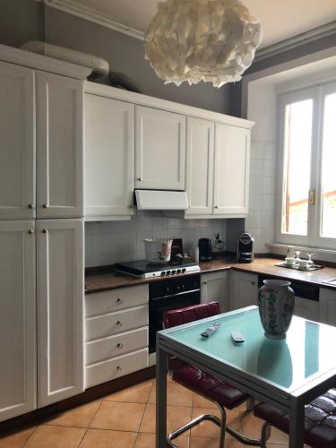 a kitchen with white cabinets and a green table at Dimora del Podestà in CastellʼArquato