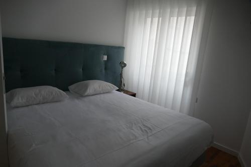 a white bed with two pillows and a window at Guest House Eça - Centro Histórico Leiria in Leiria