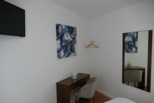 a room with a desk with two chairs and a television at Guest House Eça - Centro Histórico Leiria in Leiria