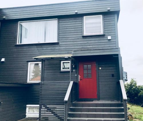 a black house with a red door and stairs at Nordhagen 17 in Stavanger