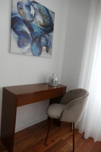 a desk with a chair and a painting on the wall at Guest House Eça - Centro Histórico Leiria in Leiria