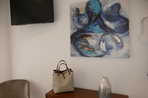 a painting on a wall next to a table with a purse at Guest House Eça - Centro Histórico Leiria in Leiria