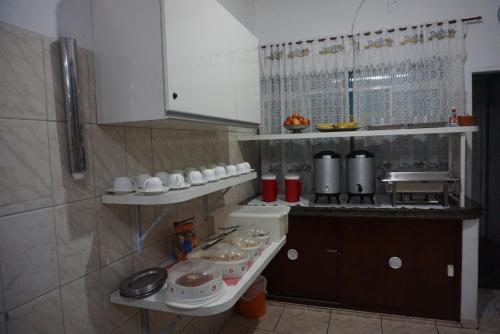 a kitchen with a counter and shelves with dishes at Pousada Orquidário in Santos