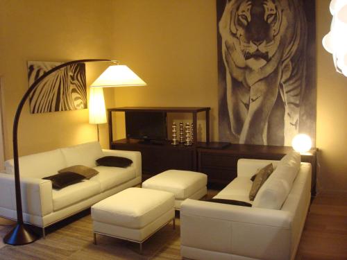 a living room with white couches and a lion painting at L'Appart 6 in Aix-en-Provence