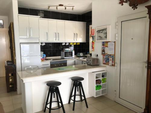 プエルト・デル・カルメンにあるHarbour Sea View Apartmentの白いキャビネットとバースツール2つ付きのキッチン