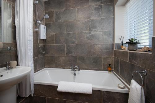 une salle de bain avec une baignoire et un lavabo dans l'établissement Lizzies Cottage, à Berwick-upon-Tweed