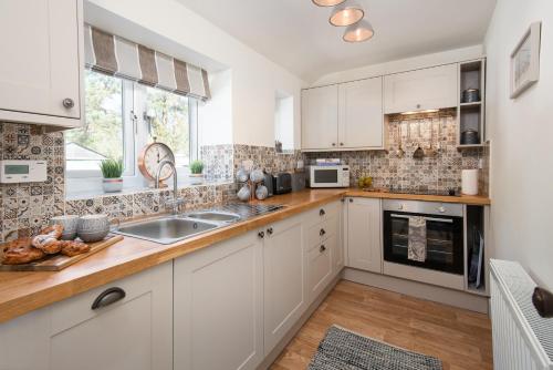 a kitchen with white cabinets and a sink at Lizzies Cottage in Berwick-Upon-Tweed