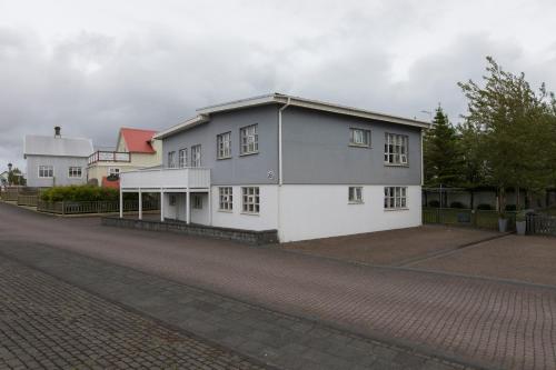 a white house with a gray roof on a street at A. Bernhard Guest House in Keflavík