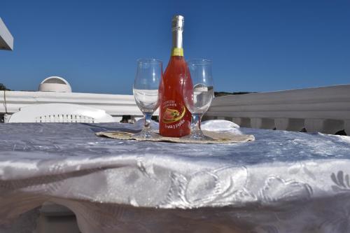 a bottle of hot sauce and two wine glasses on a table at Bisha Apartments in Ulcinj
