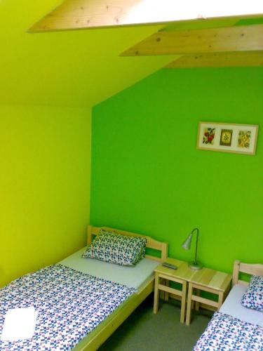 a green bedroom with two beds and a lamp at Penzion Cihelna in Brno