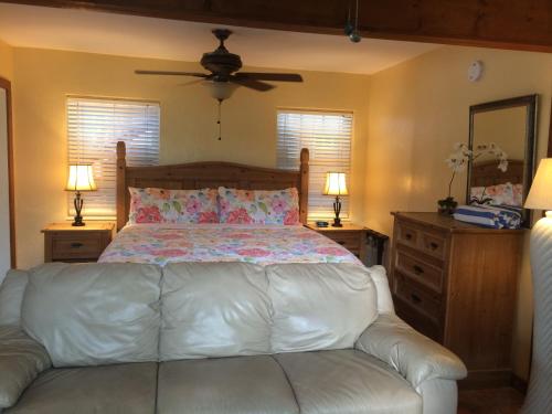 a bedroom with a bed with a white leather couch at Courtney's Place Historic Cottages & Inns in Key West