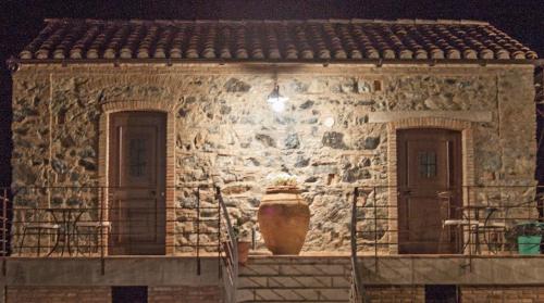 una casa de piedra con un jarrón grande en la parte delantera en La Giara B&B, en San Demetrio Corone