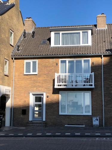 a brick house with a white balcony on it at Casa del Cisne 2 in Zandvoort