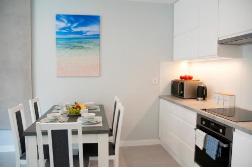 eine Küche mit einem Tisch mit Stühlen und einer Mikrowelle in der Unterkunft Gold Platinium apartament z widokiem na morze in Rewal