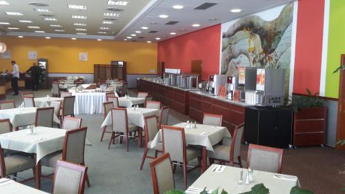 a restaurant with white tables and chairs and a bar at Exclusive HOTEL Lipno Wellness & SPA in Frymburk