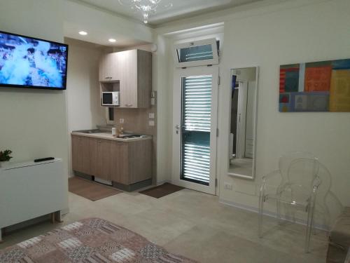 a kitchen with chairs and a television on the wall at Guest House B&B Via Marina in Reggio Calabria