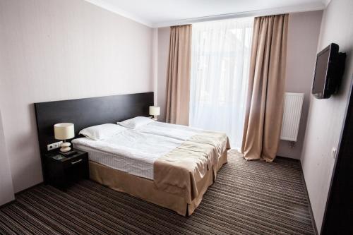 a hotel room with a bed and a television at Optima Sumy in Sumy