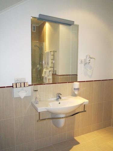 a bathroom with a sink and a mirror at Optima Collection Kharkiv Hotel in Kharkiv