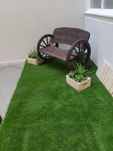 a bench sitting on the grass with two plants at Terlon Apartments in Liverpool