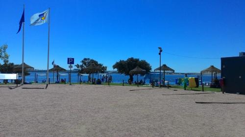 a beach with a flag and umbrellas and the water at Monte dos Velhos in Reguengos de Monsaraz