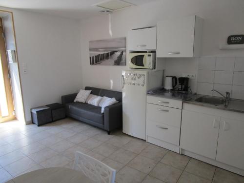 a kitchen and a living room with a couch at maisonnette avec jardin proche du Mont Saint Michel in Pontorson