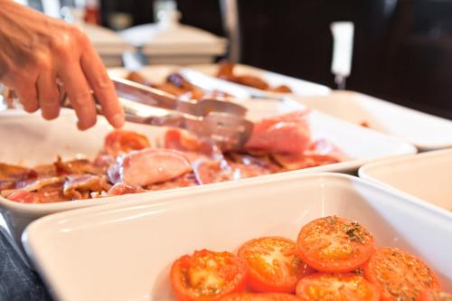 a person reaching into a tray of food with tomatoes at Bournemouth East Cliff Hotel, Sure Hotel Collection by BW in Bournemouth