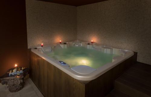 King Maron Wellness Beach Hotel في مارونيا: حمام مع حوض استحمام مع الشموع فيه