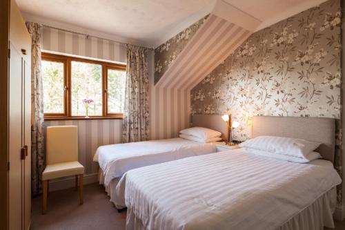 2 Betten in einem Zimmer mit 2 Fenstern in der Unterkunft Langdon Farm Guest House in Saundersfoot