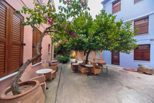 un patio con mesas, sillas y un árbol en KasteliSuites, en La Canea