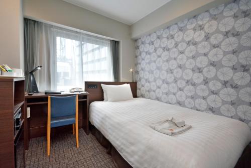 a hotel room with a bed and a desk and a window at Premier Hotel Cabin Shinjuku in Tokyo