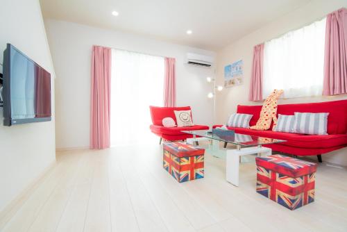 a living room with red chairs and a table at Kourijima L'hotels in Nakijin