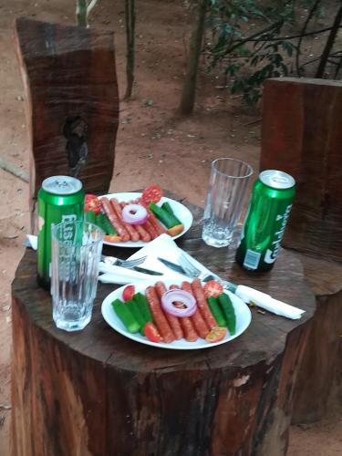 a table with two plates of food and two soda cans at Hidden Jungle Village in Wilpattu