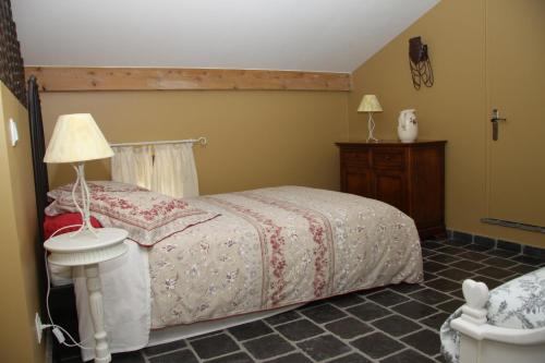 a bedroom with a bed and a table with a lamp at La Bastide de Fontaille in Saint-Félicien