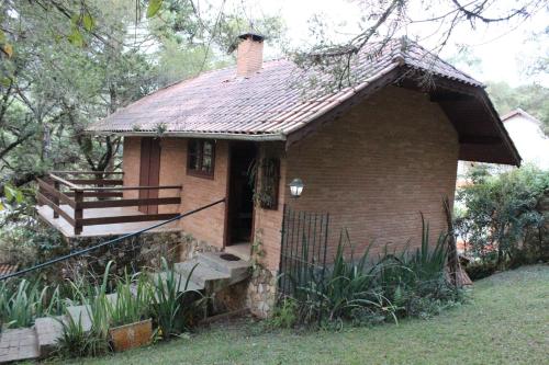 een klein bakstenen huis met een veranda en een trap bij Chales Chez Nous in Monte Verde