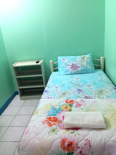 a bedroom with a bed with a floral bedspread at NAT 2 Guest House in Bangkok