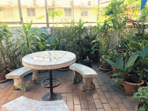 a patio with a table and two benches and plants at NAT 2 Guest House in Bangkok