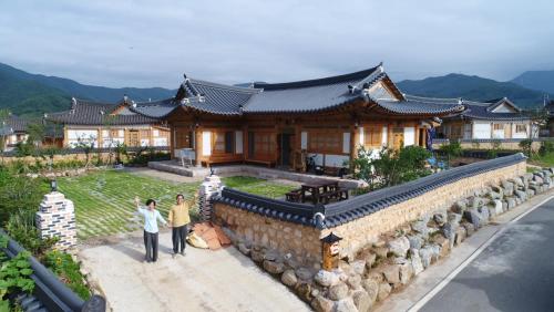 two people are standing in front of a house at Mirinae Hanok Tradiational House in Gwangyang