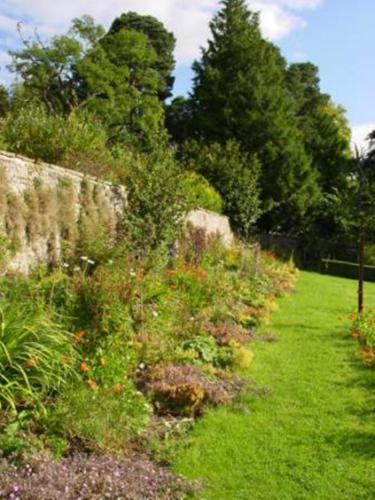 a garden with flowers and a stone wall at Loch Ness Country House Hotel in Inverness