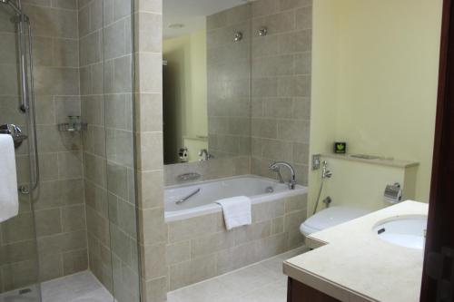 a bathroom with a tub and a sink and a toilet at Ramada by Wyndham Downtown Dubai in Dubai