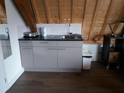 uma cozinha com armários brancos e um lavatório em B&B Museumkwartier Schiedam em Schiedam
