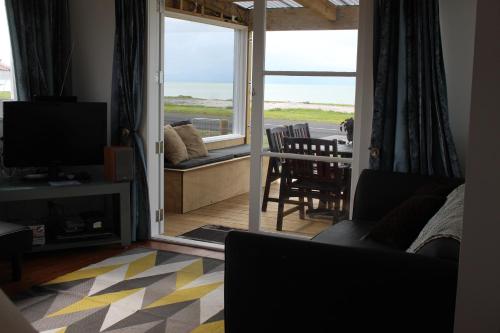 uma sala de estar com uma porta de vidro deslizante para um pátio em Sea Urchin Cottage em Miranda