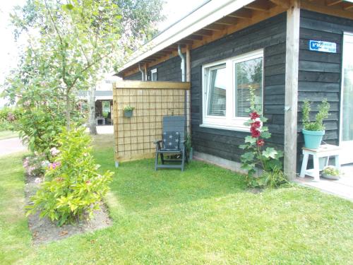 a house with a window and a chair in the yard at Middenpaed in Balk