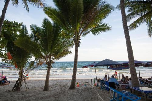 people sitting under umbrellas on a beach with palm trees at Mosaic Condminum A24m by malai in Mae Pim