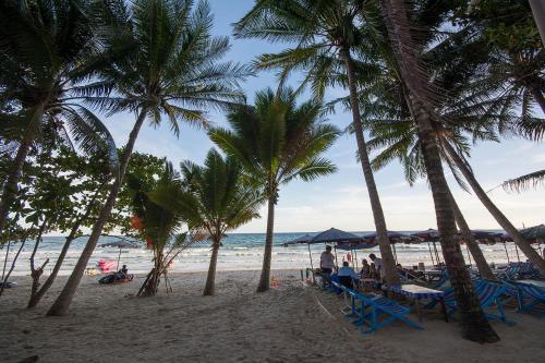 people sitting on the beach under palm trees at Mosaic Condminum A24m by malai in Mae Pim