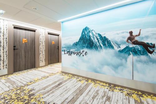 a room with a wall mural of a man on a swing at Ibis Styles Sallanches Pays du Mont-Blanc in Sallanches