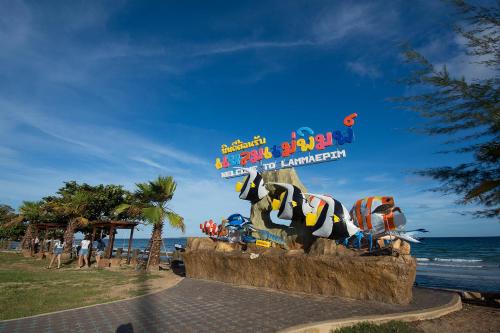 a sign in front of the beach with a dog statue at Grandblue Condo 410 in Mae Pim
