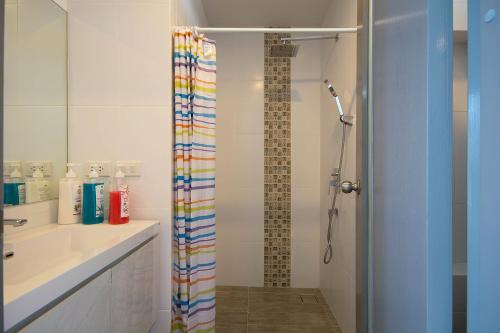 a bathroom with a shower with a rainbow shower curtain at Grandblue Condo 410 in Mae Pim