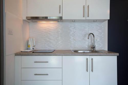 a kitchen with white cabinets and a sink at Grandblue Condo 410 in Mae Pim