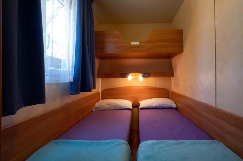 a small room with two beds and a window at Ca' Berton Village in Cavallino-Treporti