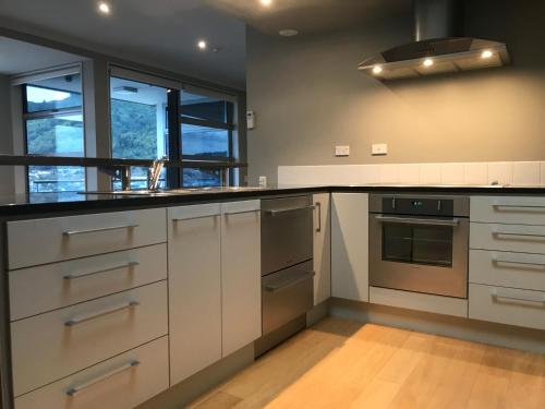 cocina con armarios blancos y encimera negra en Astonishing Views Superb Waterfront Apartment en Picton
